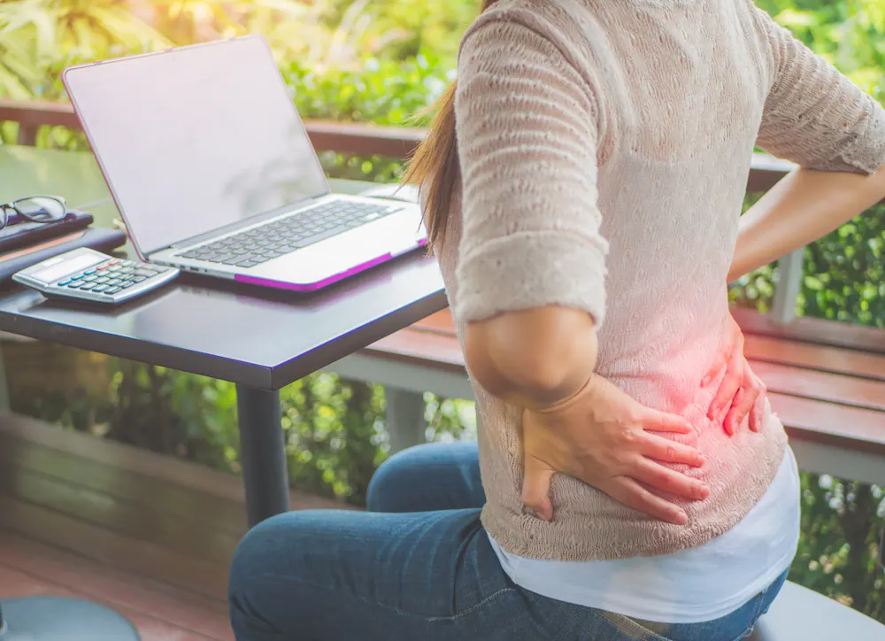 a woman suffering from lower back pain while working