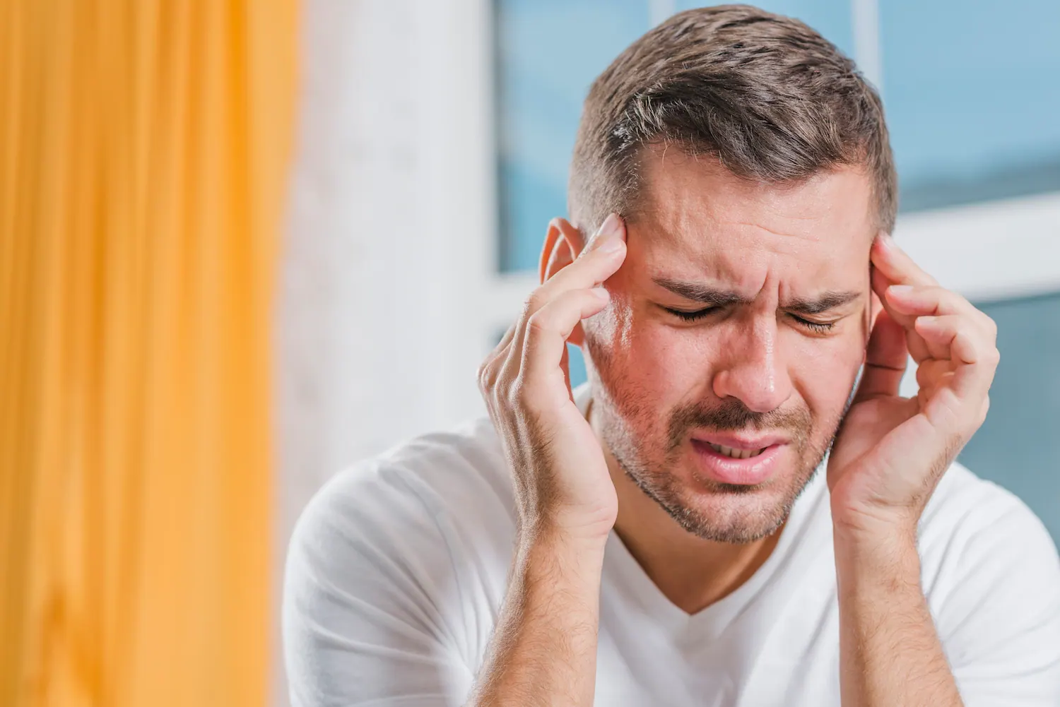 man holding his head due to pain