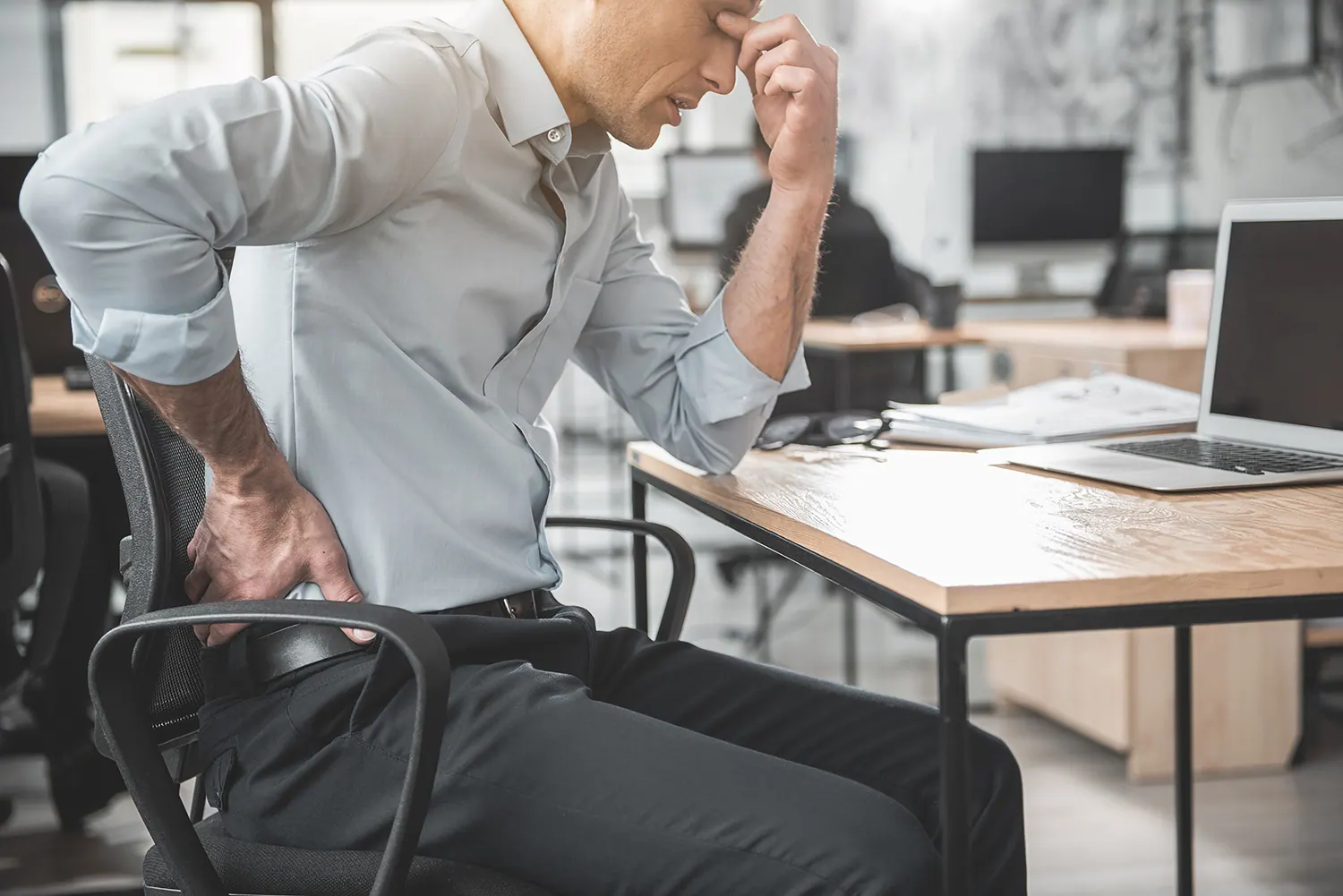 a man suffering from pinched nerve while sitting and working