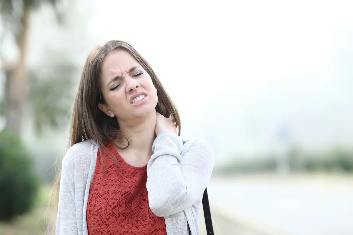 a woman suffering from neck while walking
