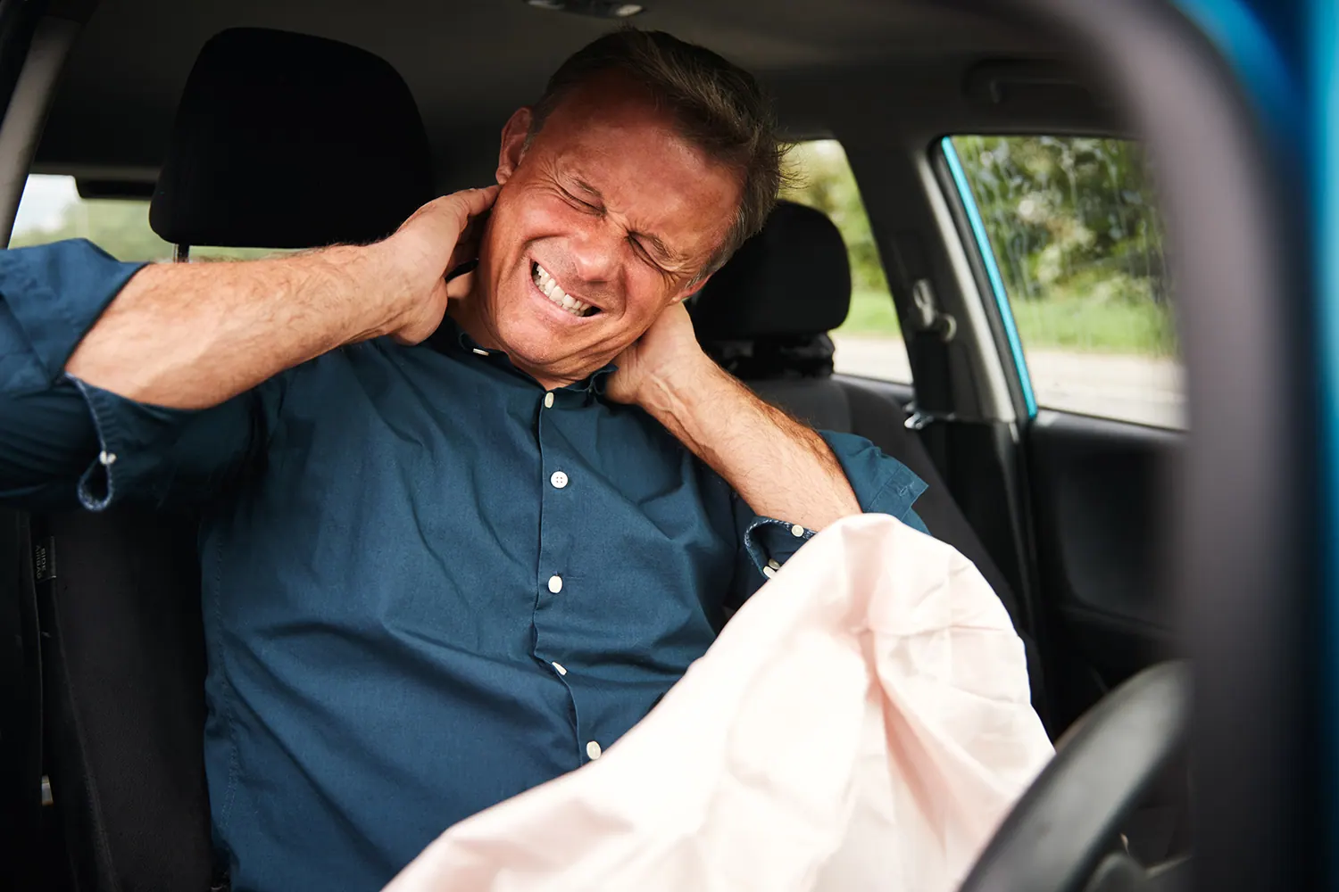 a man suffering from whiplash inside his car after the accident\