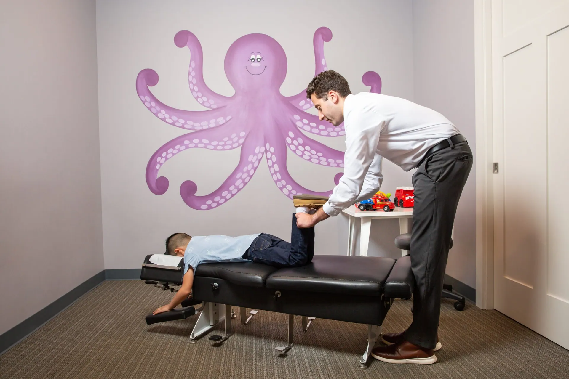 a chiropractor giving his patient child a knee pain treatment